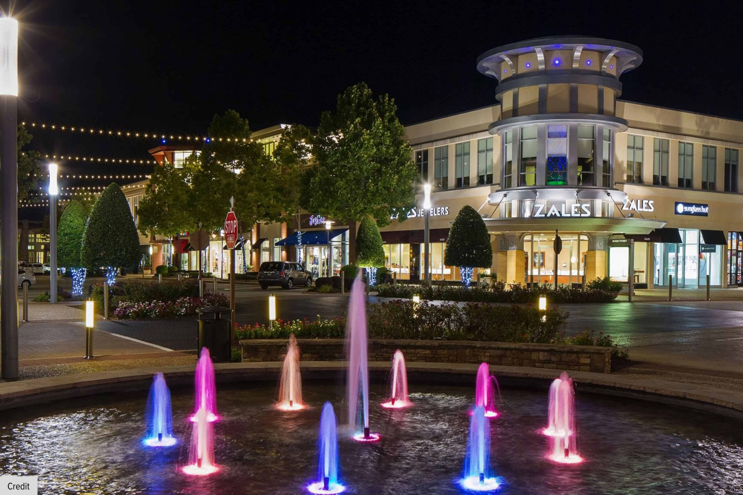 Pinnacle Hills Promenade illuminated at night with fountains, shopping, and entertainment.